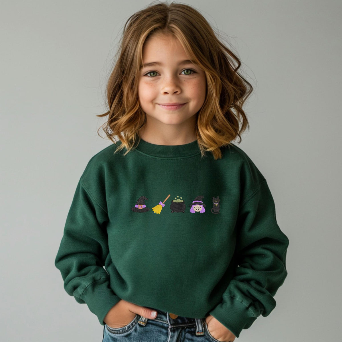 Child wearing a forest green Little Witch embroidered youth sweatshirt
